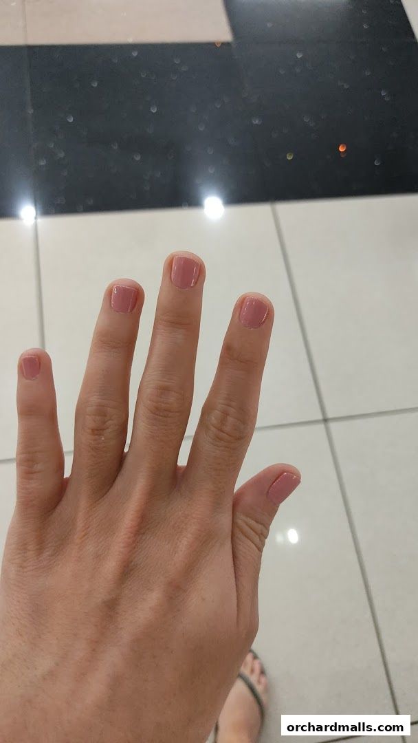 A hand with perfectly manicured nails painted in a soft pink shade.