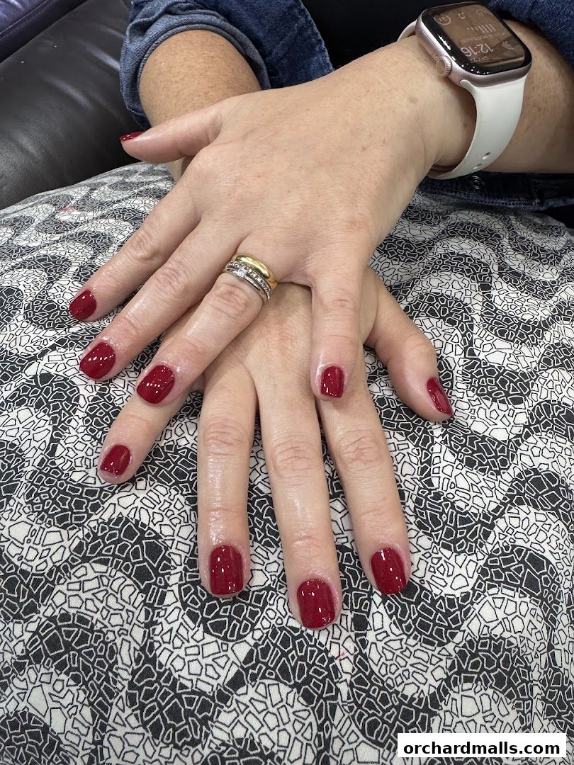 Close-up of hands with perfectly manicured, dark red nails and rings.