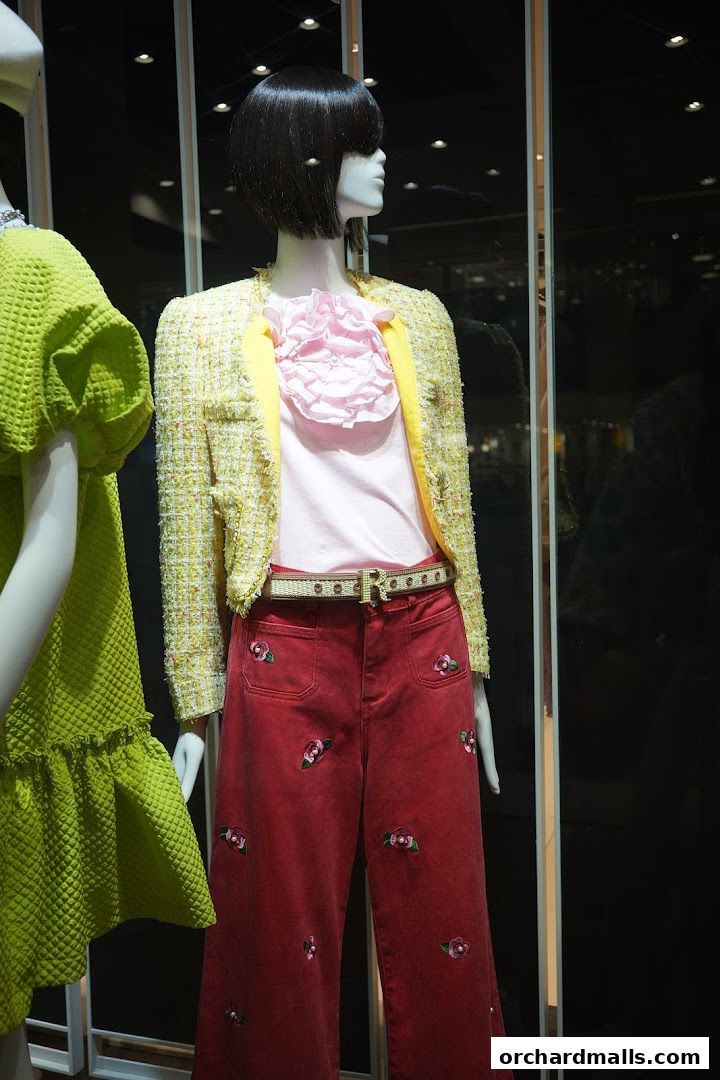 Mannequins display a yellow tweed jacket, pink top, and red embroidered pants.