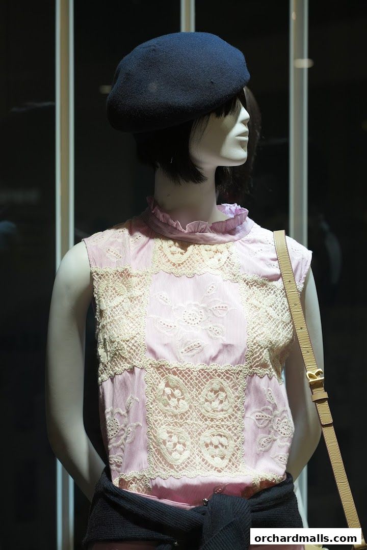 Mannequin wearing a pink striped top with lace details and a blue beret.