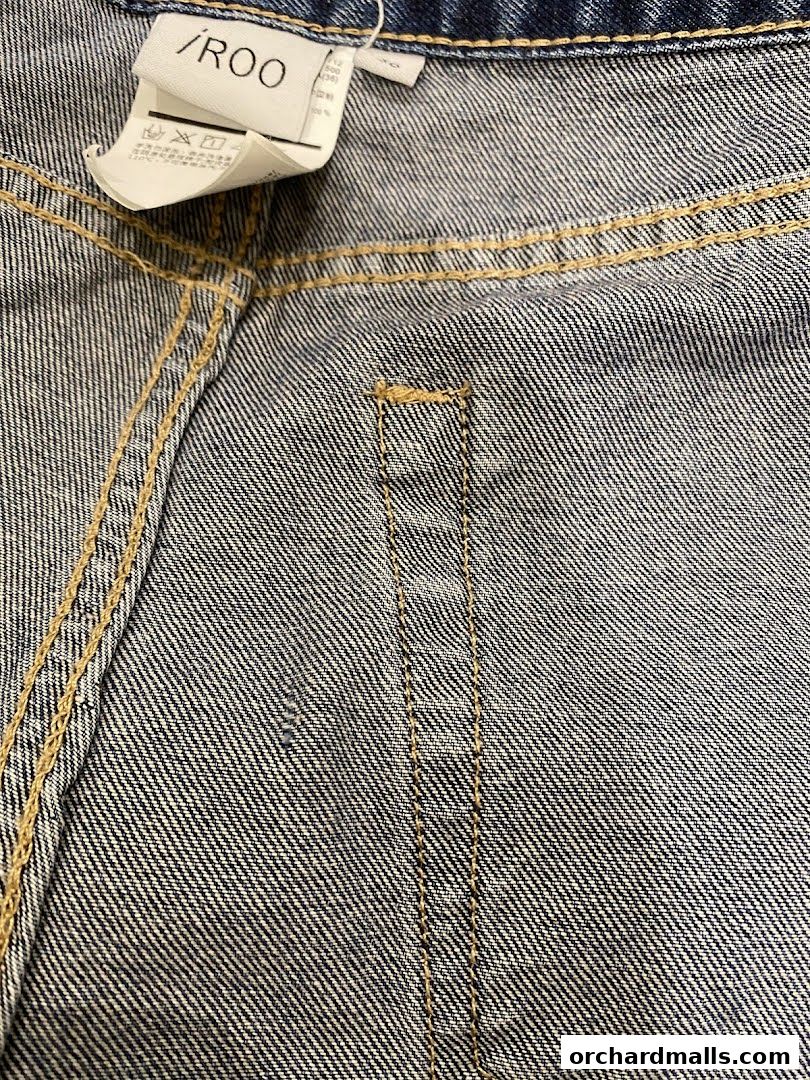 Close-up of denim jeans with visible stitching and a brand tag.
