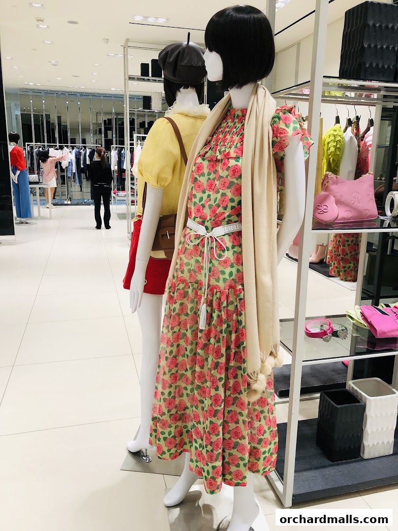 Mannequins display floral dresses and accessories in a bright retail store.