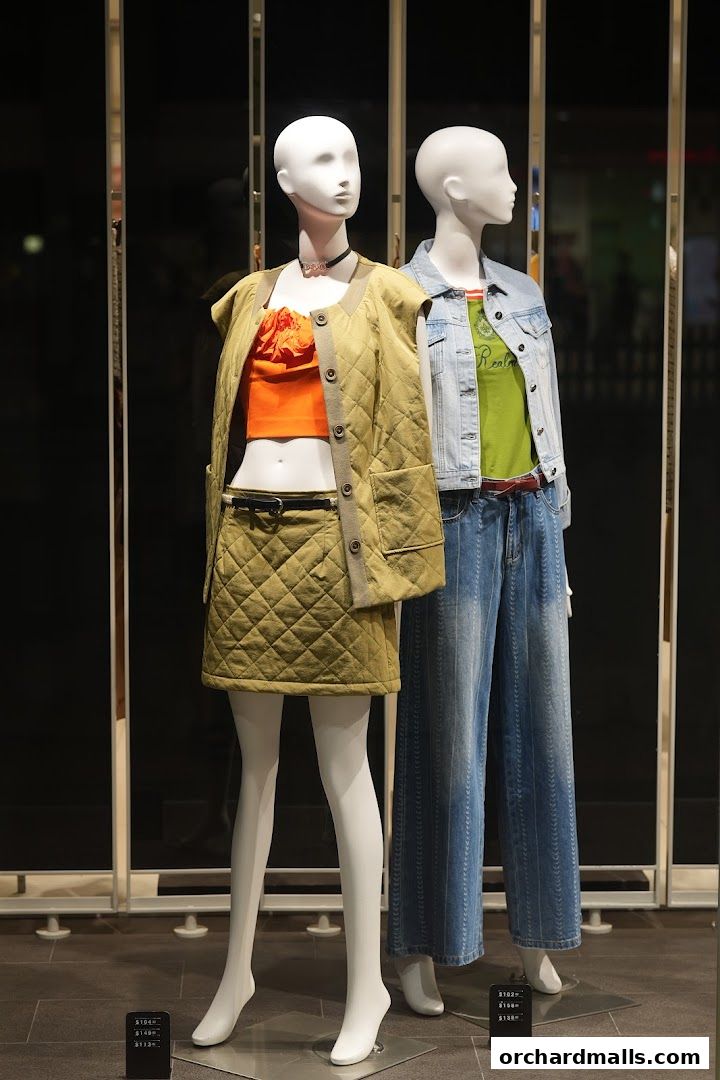 Mannequins display fashionable outfits in a retail store window.