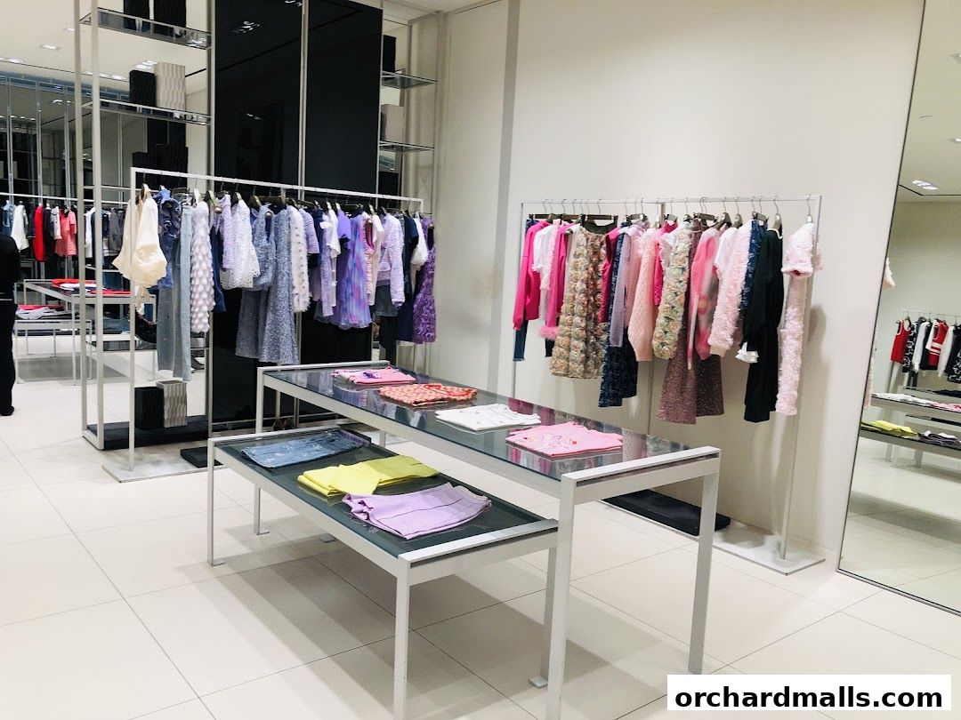 Interior view of a clothing store with racks of colorful apparel and display tables.