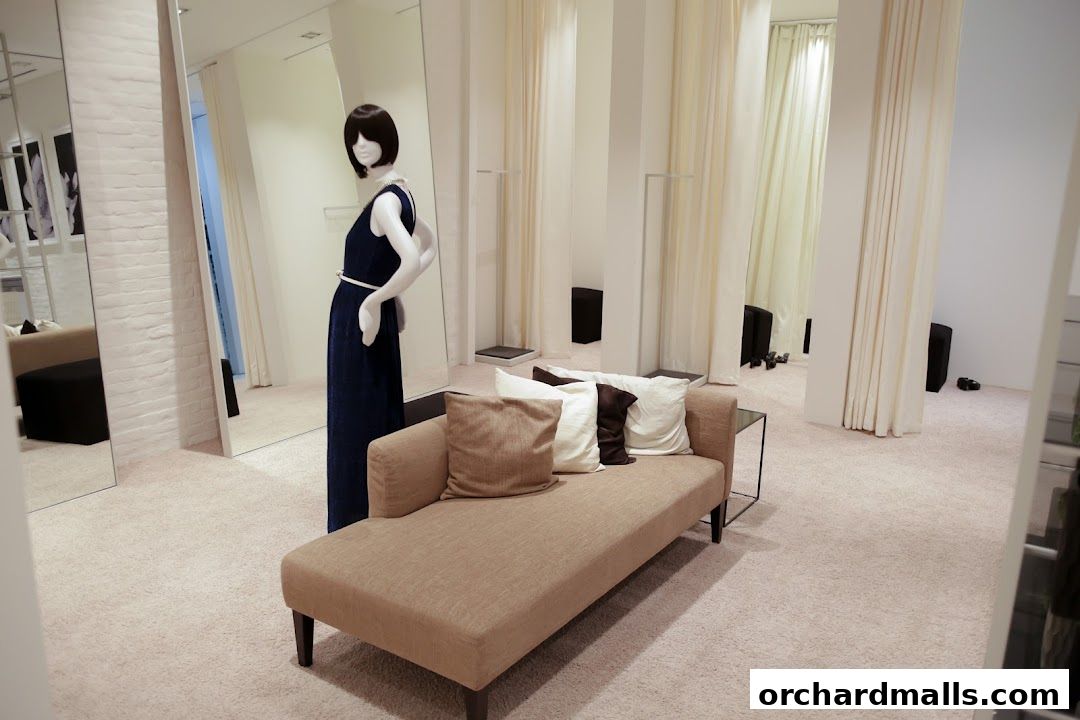 Interior of a clothing store with a mannequin, sofa, and fitting room curtains.