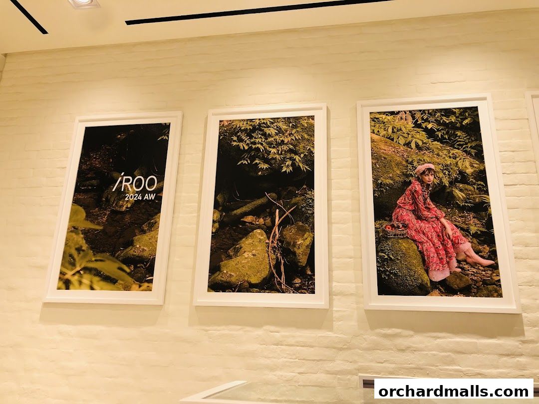 Three framed artworks featuring nature scenes and a model, displayed on a brick wall.