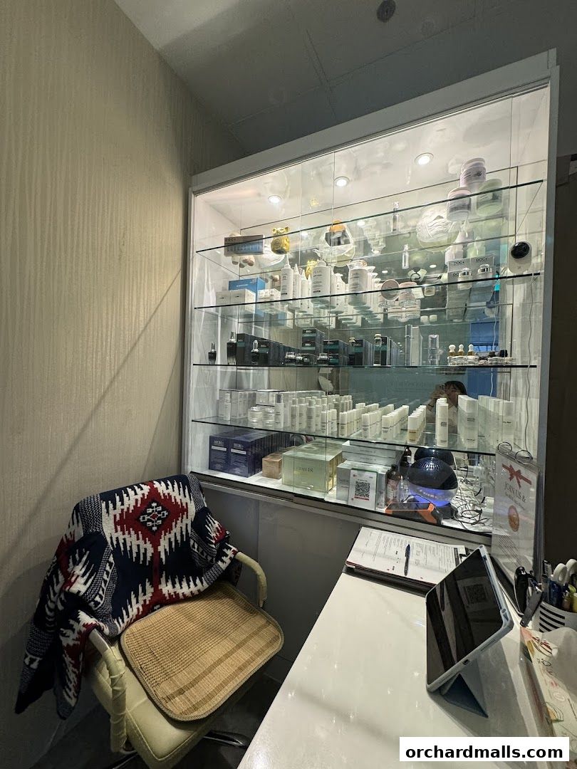 A display cabinet filled with skincare products and a chair with a blanket.