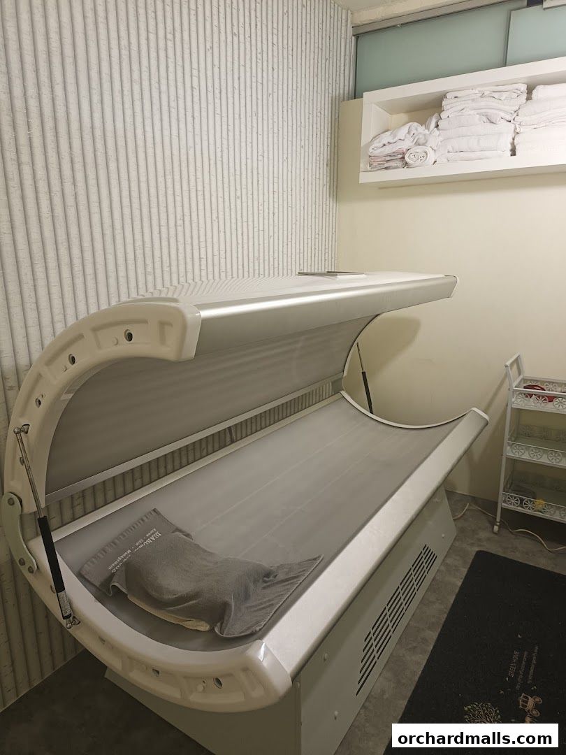 A tanning bed with towels neatly stacked on a shelf above.