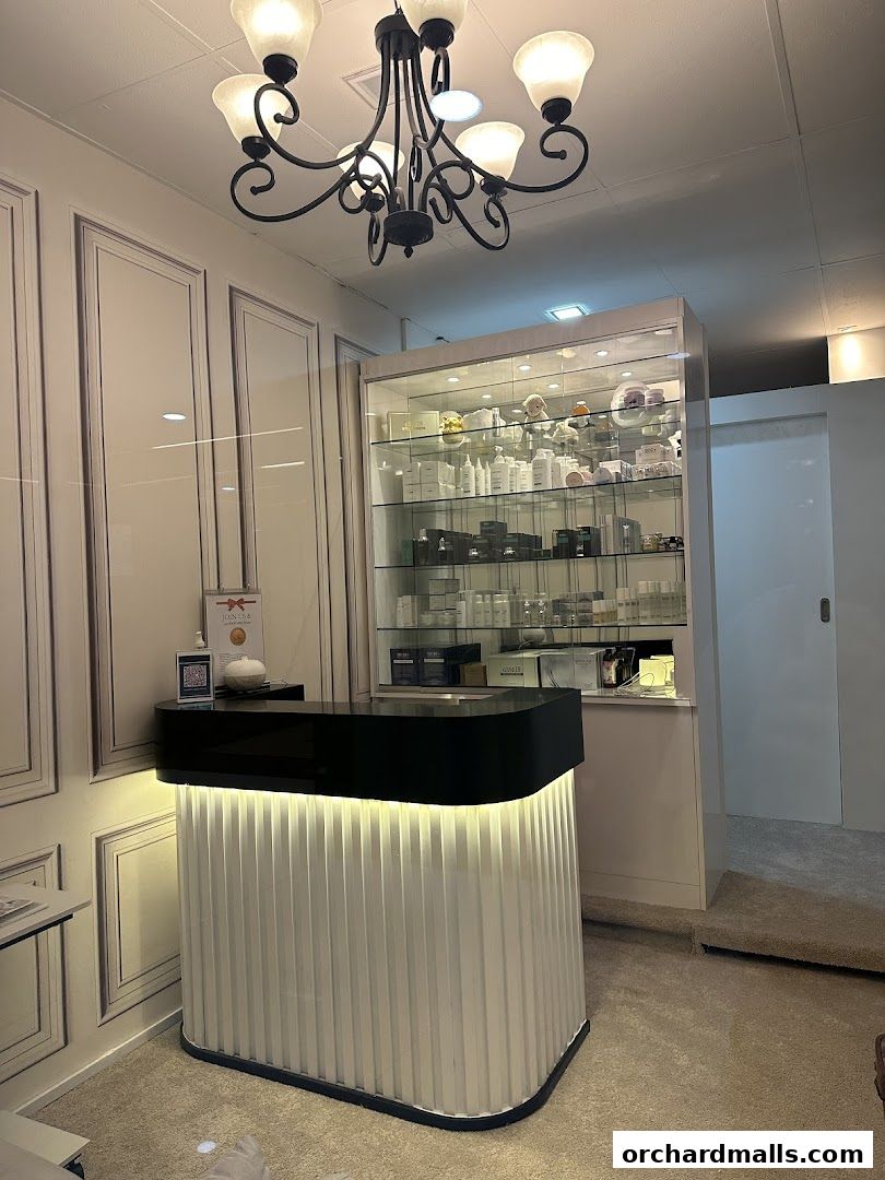 A modern reception desk and display shelves filled with beauty products in a clean aesthetic clinic.