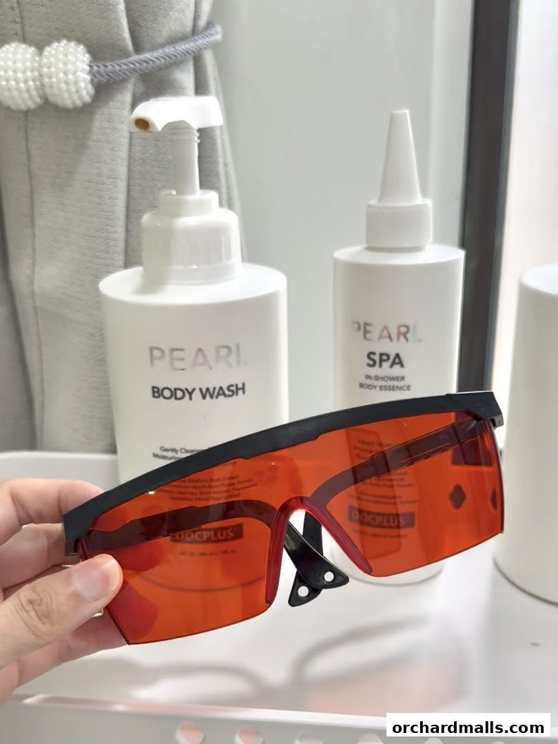 A hand holds red-tinted protective glasses in front of beauty products.