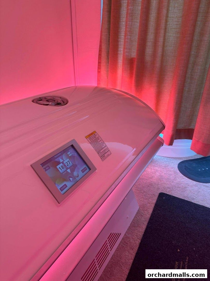 A tanning bed with a digital display and pink LED lighting.