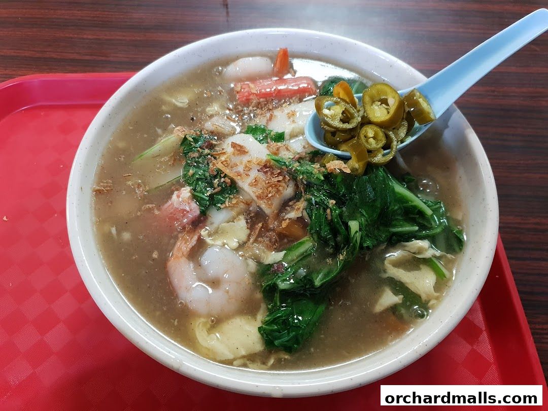 A close-up shot of a delicious bowl of noodle soup with shrimp and vegetables.