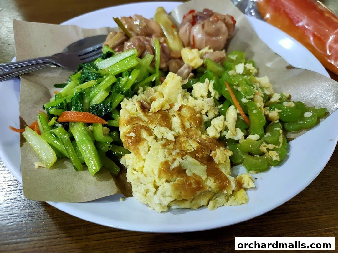 A plate of food with scrambled eggs, stir-fried vegetables, and chicken.