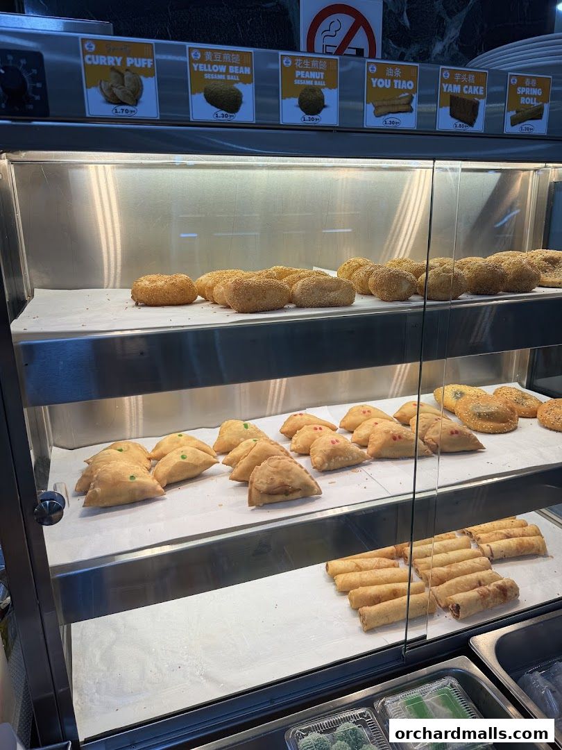 A display case filled with various pastries and snacks, with labels and prices visible.