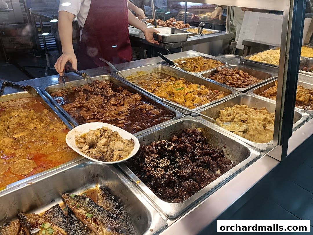 A variety of food dishes displayed in metal trays at a buffet-style eatery.