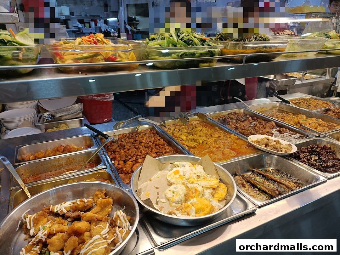 A display of various cooked dishes and fresh vegetables in a food stall.