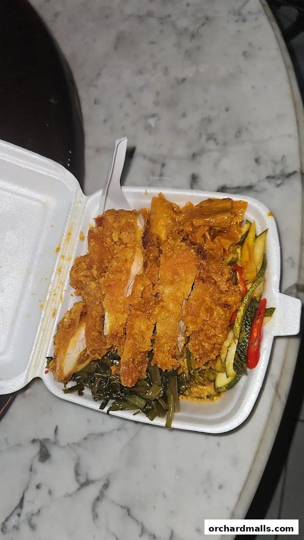 A takeaway container filled with crispy chicken, vegetables, and a curry sauce.