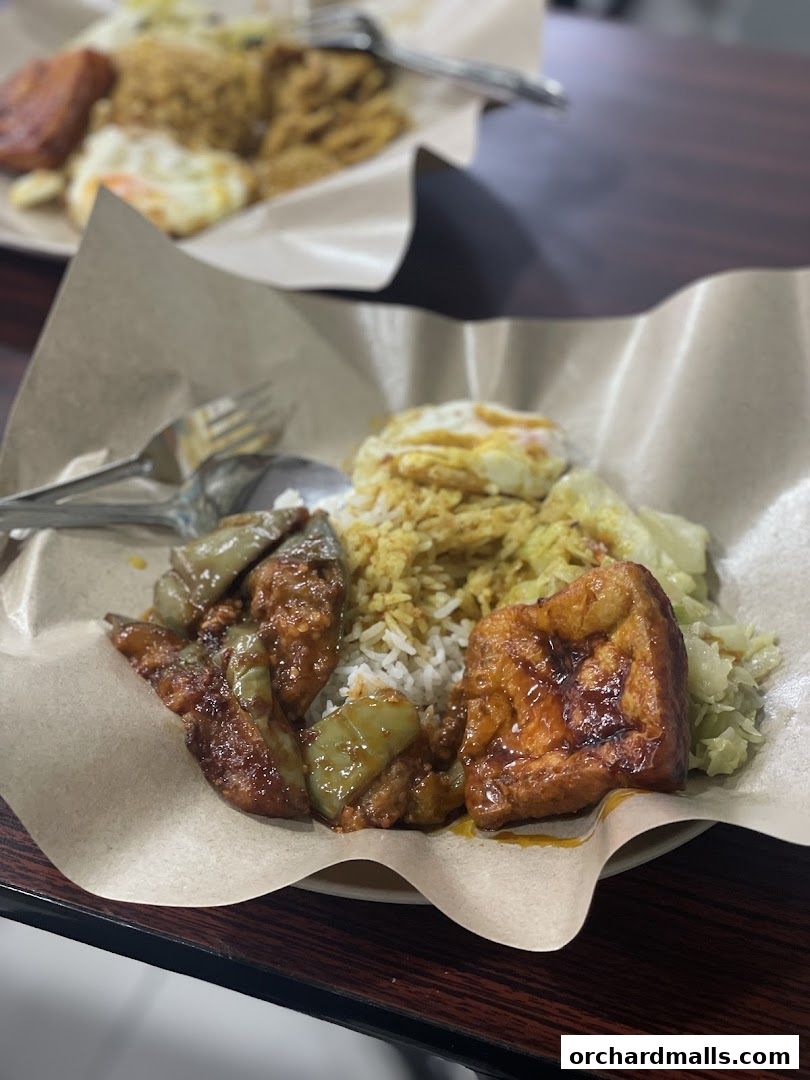 A close-up of a delicious meal served on brown paper, featuring rice, fried egg, and various side dishes.