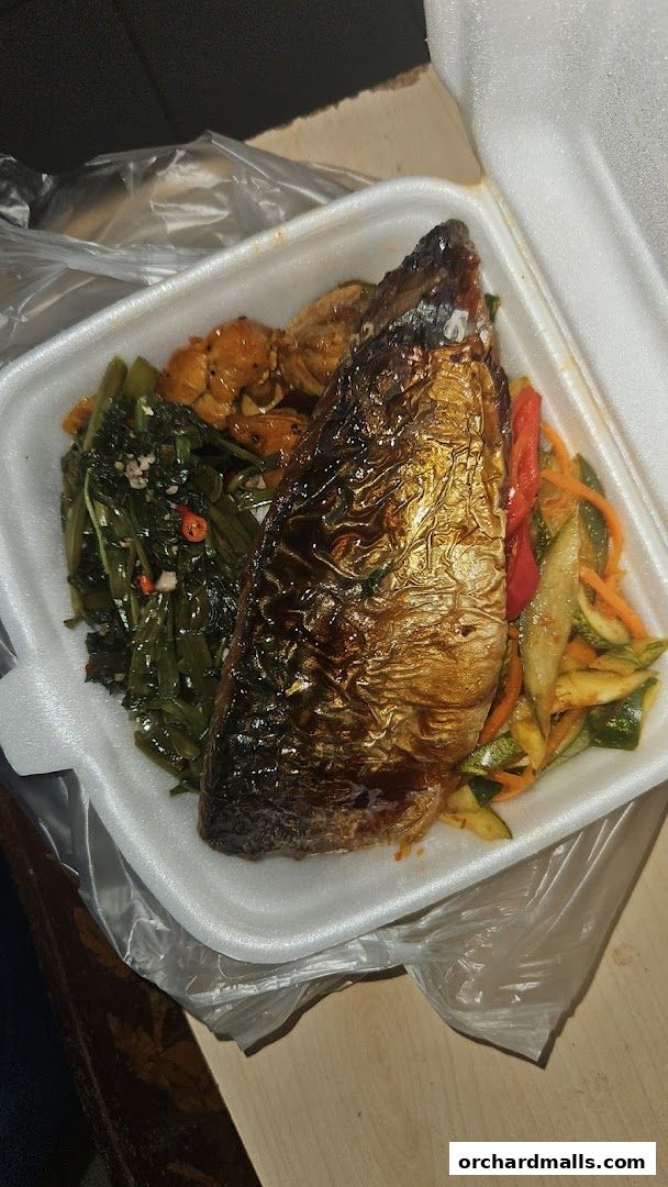 A take-out container filled with a grilled fish, stir-fried vegetables, and other side dishes.