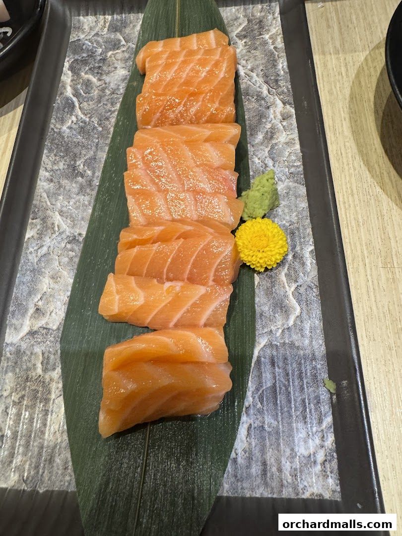 A plate of fresh salmon sashimi with wasabi and a decorative flower.