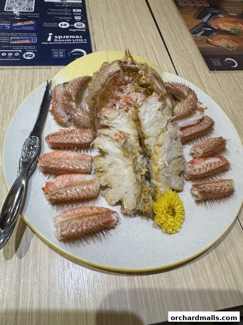 A plate of cooked hairy crab with legs and body, garnished with a yellow flower.