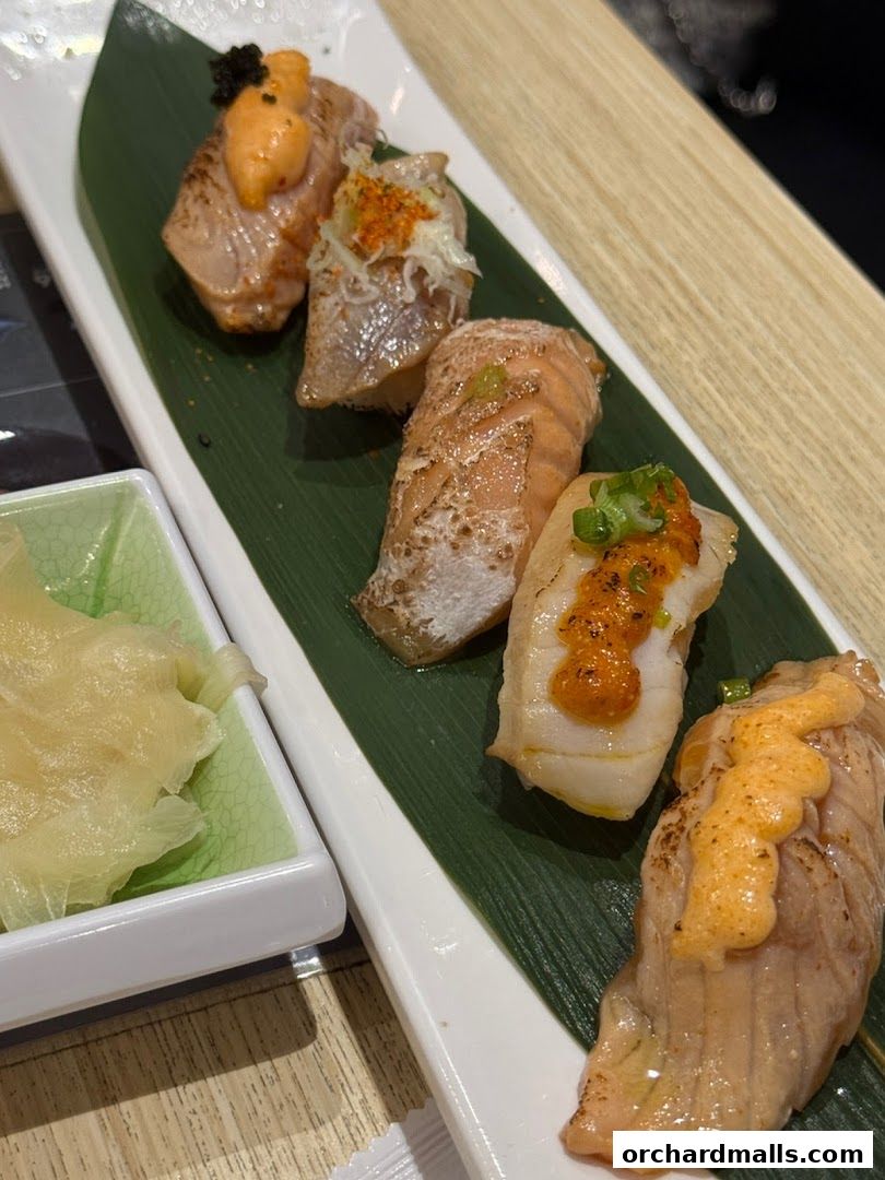 A plate of five pieces of sushi with various toppings and a side of pickled ginger.