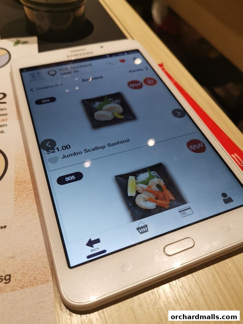 A tablet displays a digital menu for Itacho Sushi, showing sashimi dishes.