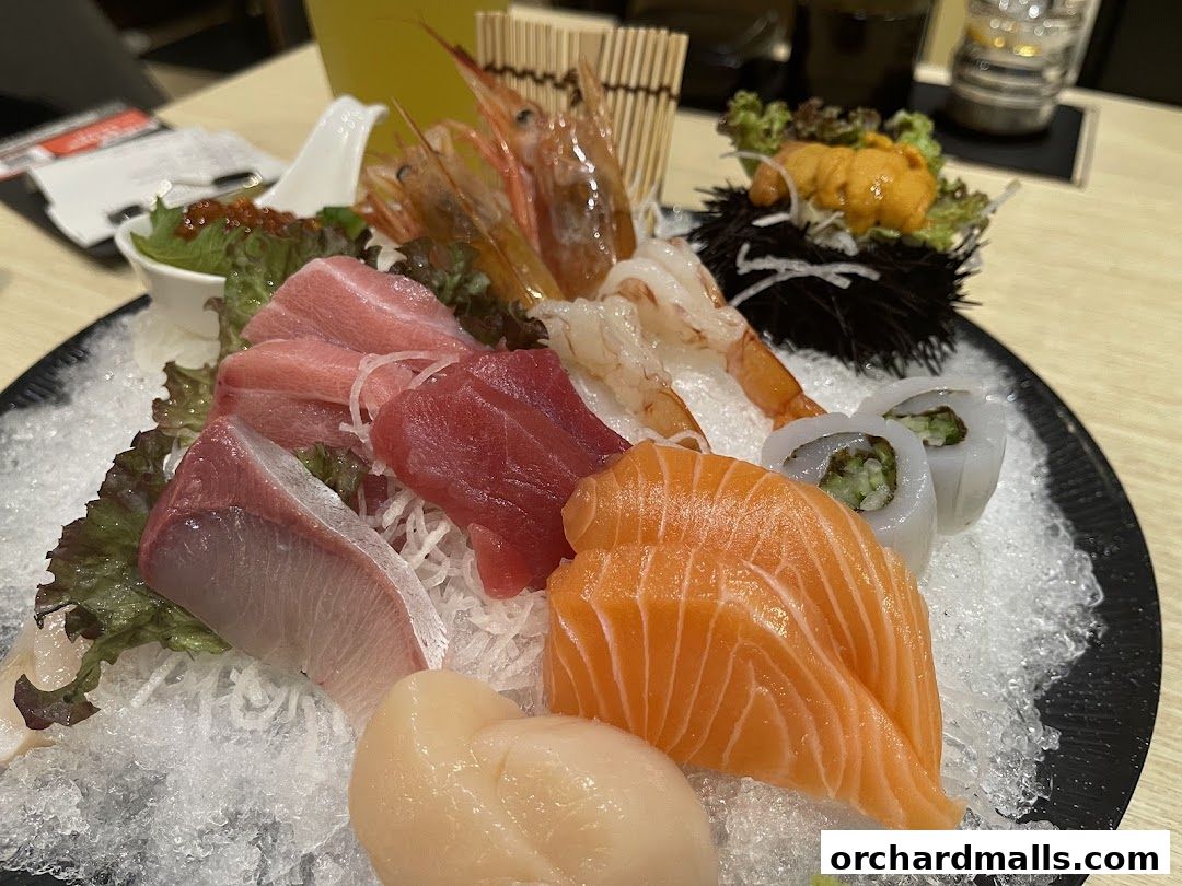A platter of assorted sashimi and sushi, including salmon, tuna, shrimp, scallop, uni, and squid.