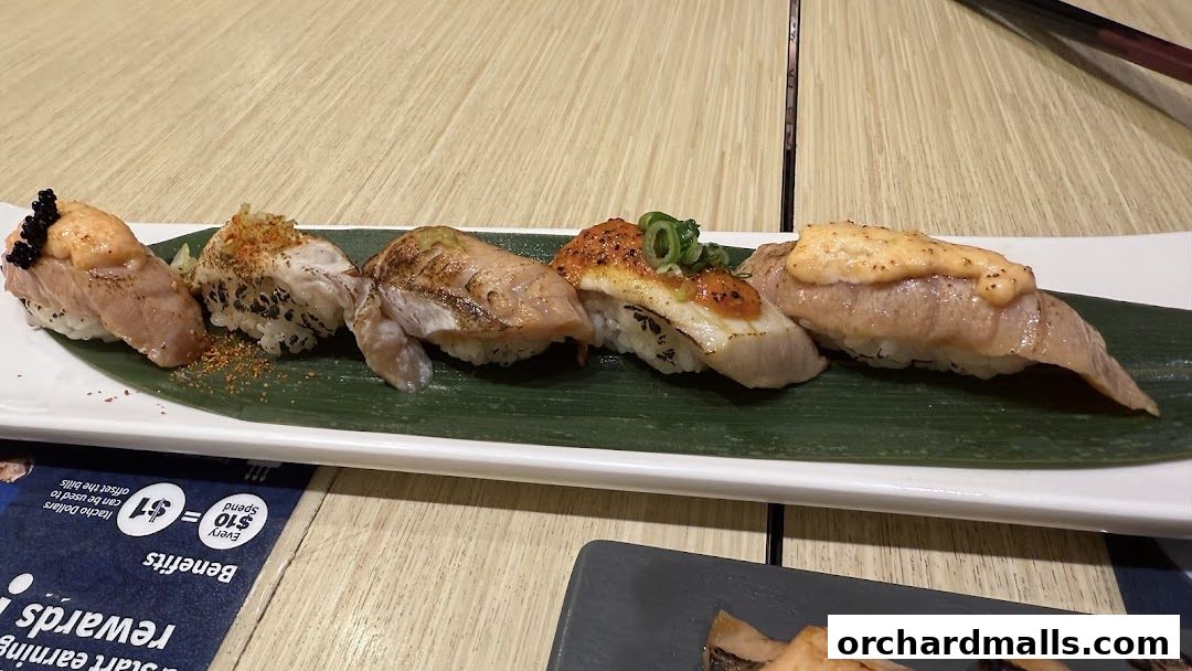 A plate of assorted sushi with various toppings and garnishes on a banana leaf.