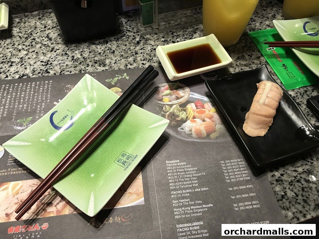A table setting at Itacho Sushi with sushi, chopsticks, and a drink.
