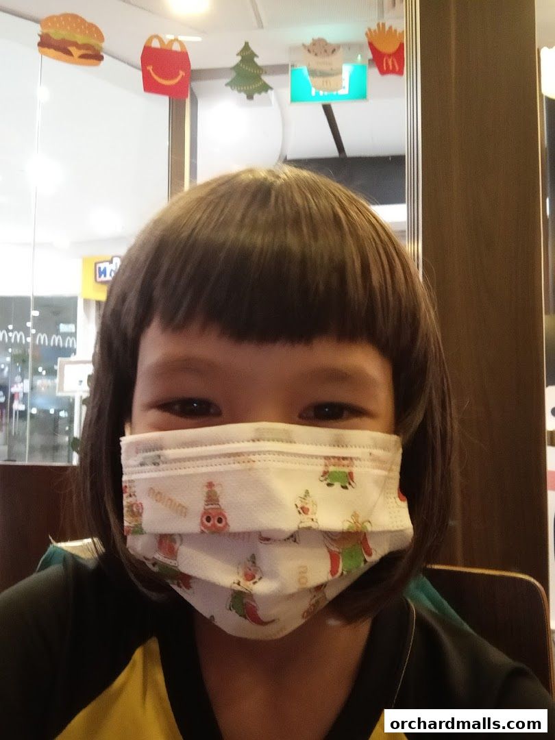 A child wearing a festive face mask with a bowl cut hairstyle.