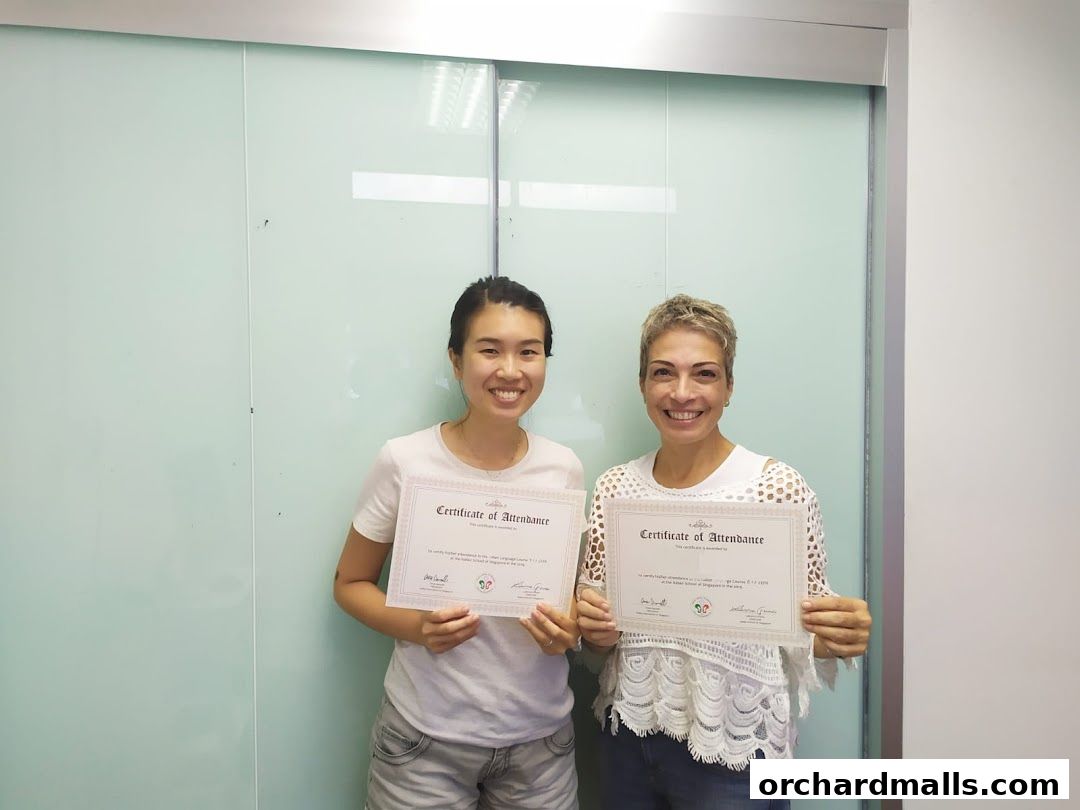 Two smiling women hold certificates of attendance from an Italian language school.