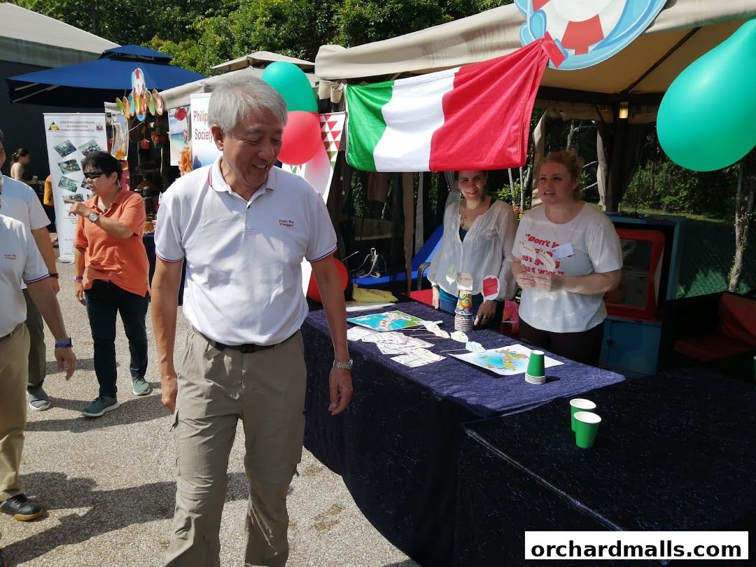 People at an outdoor event with Italian flag and balloons, promoting an Italian language school.