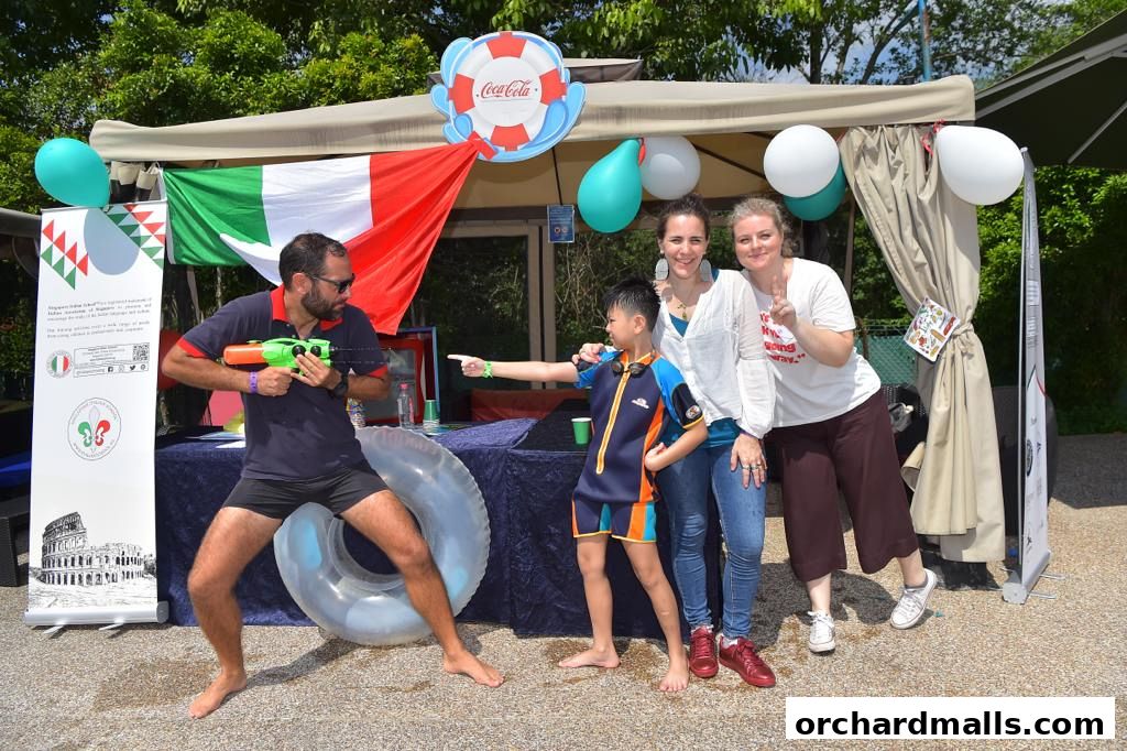 People posing with water guns and Italian flags at an outdoor event.