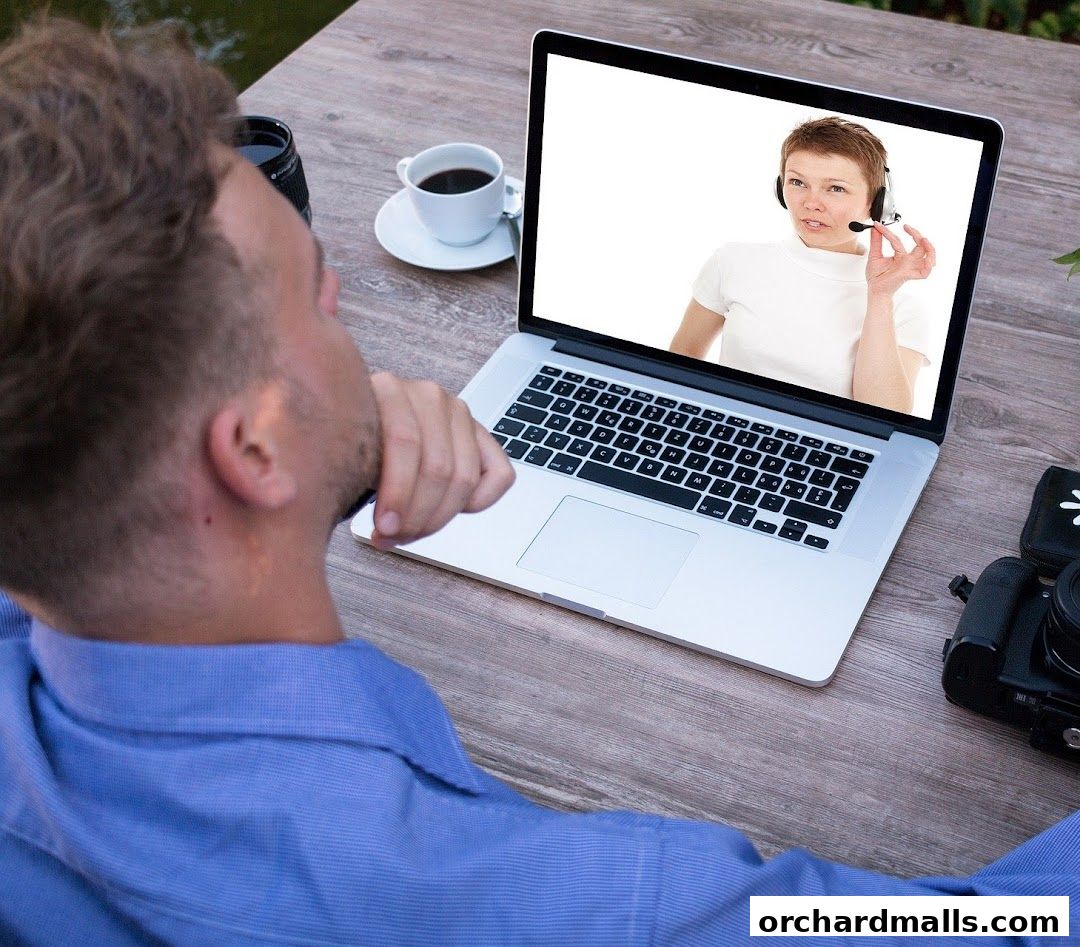 Man on a laptop with a woman wearing a headset on screen.