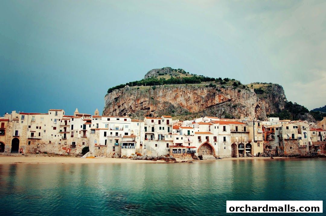 A picturesque coastal town with white buildings nestled against a dramatic cliff.