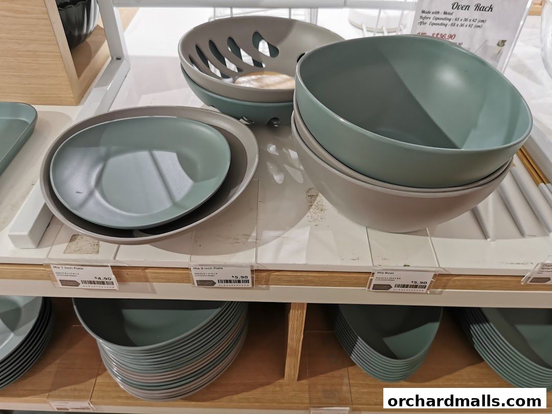 Display of modern, minimalist kitchenware including plates and bowls in muted colors.