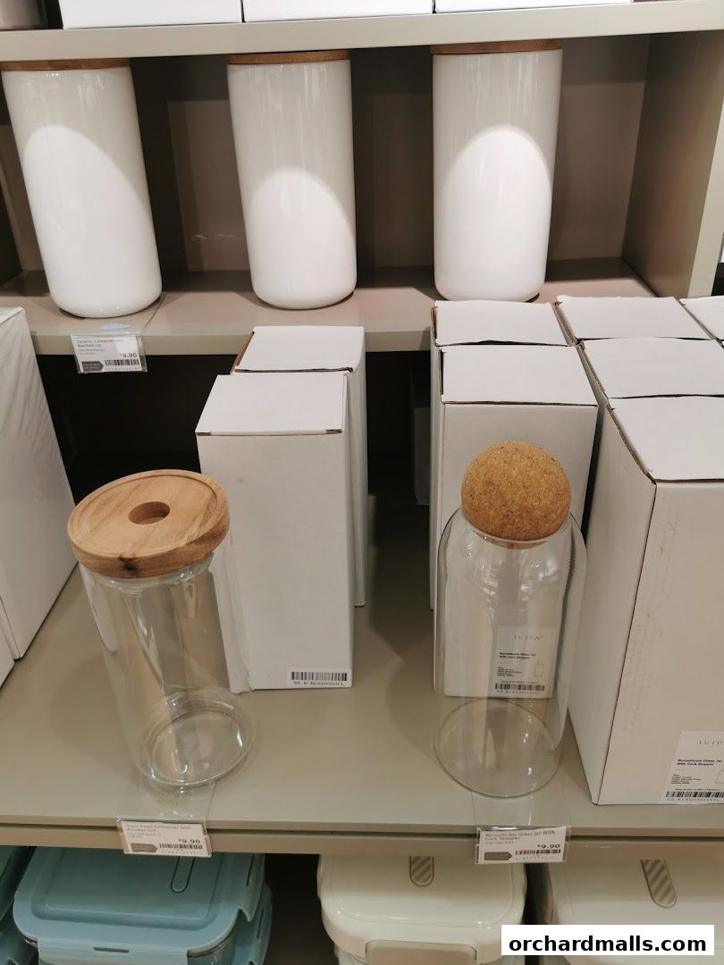 Shelves display white ceramic canisters and clear glass jars with wooden and cork lids.