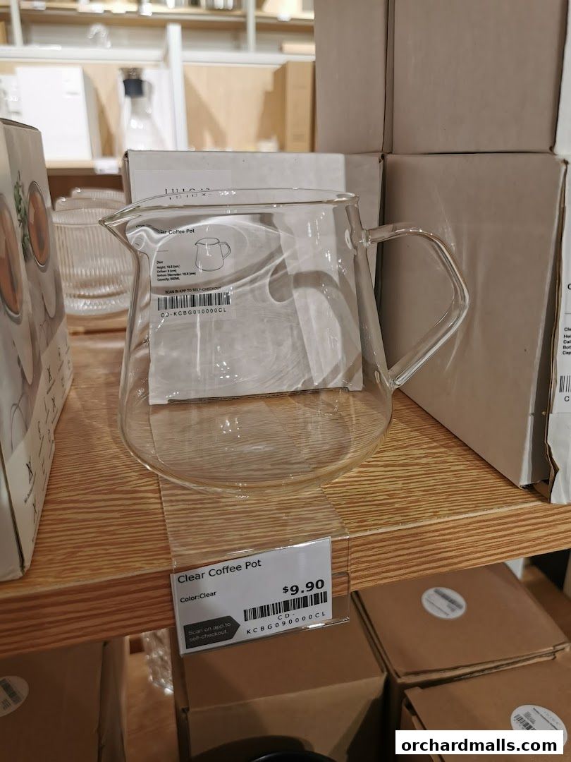 A clear glass coffee pot displayed on a wooden shelf with a price tag.
