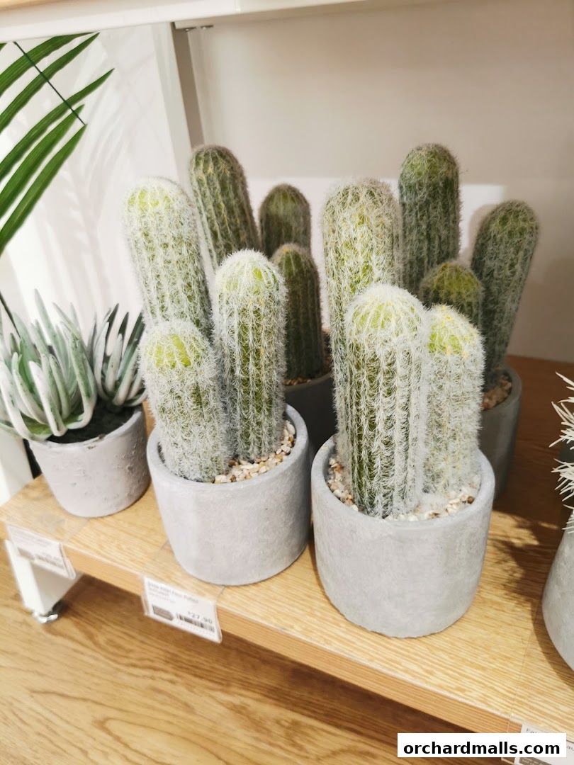 Artificial cacti and succulents in concrete pots displayed on a wooden shelf.