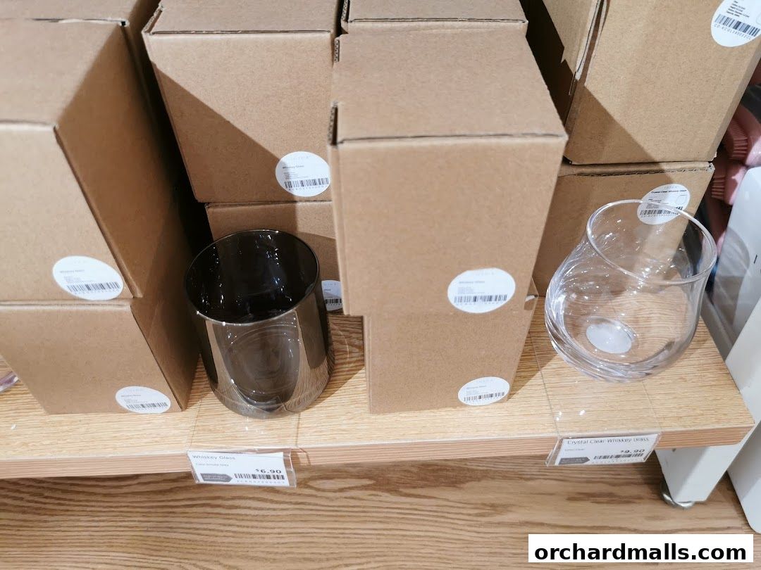 Display of boxed glassware, including whiskey glasses, on a retail shelf.
