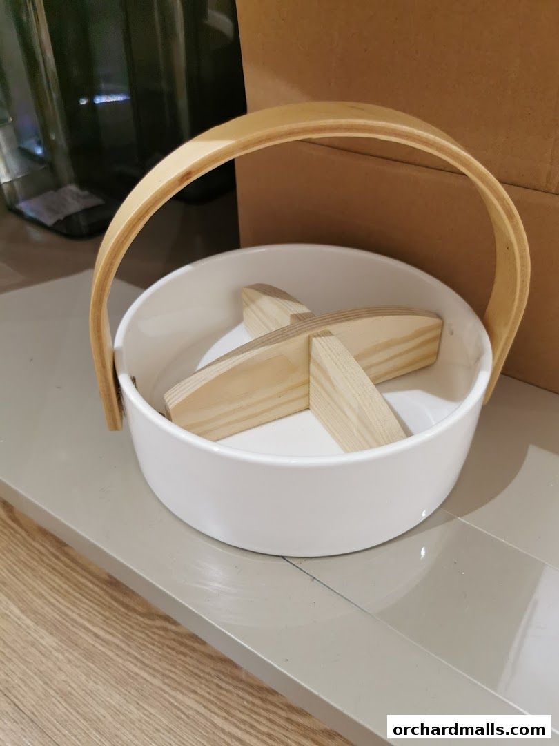 A white ceramic bowl with a wooden handle and wooden dividers inside.