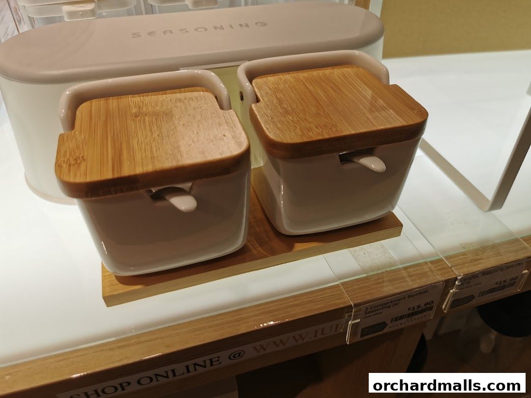 Two ceramic seasoning jars with bamboo lids on a wooden stand.