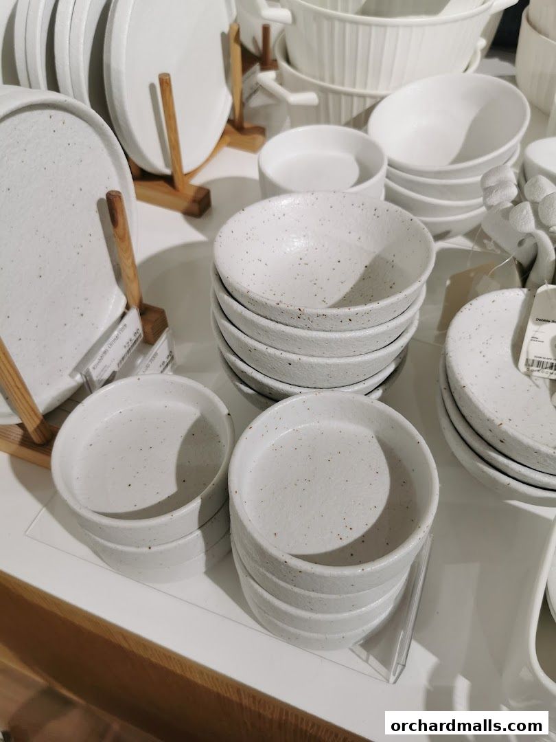 A display of white ceramic bowls and plates with speckled detailing.