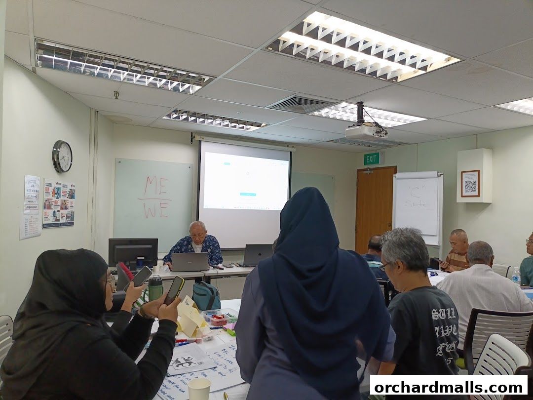 People attending a class or workshop with a projector screen and whiteboard.