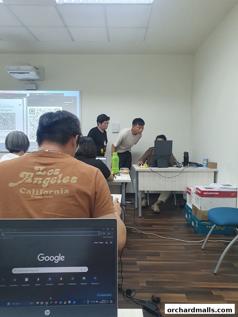 People in a classroom setting looking at a screen and a laptop.