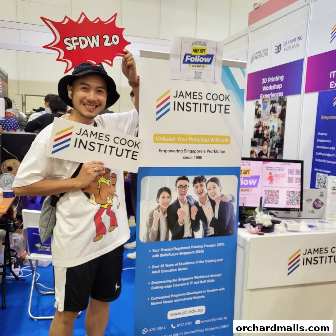 A man holds signs for James Cook Institute at an event, promoting their training programs.
