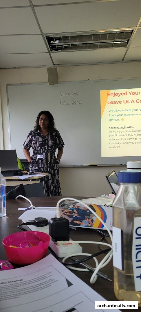 A woman stands in front of a whiteboard with a presentation slide about reviews.