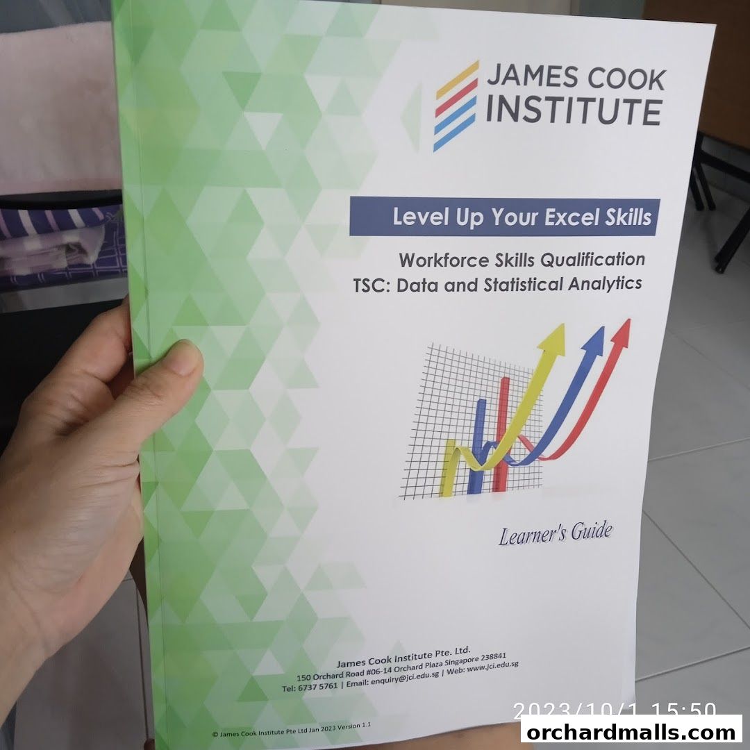 A hand holds a learner's guide from James Cook Institute about Excel skills.