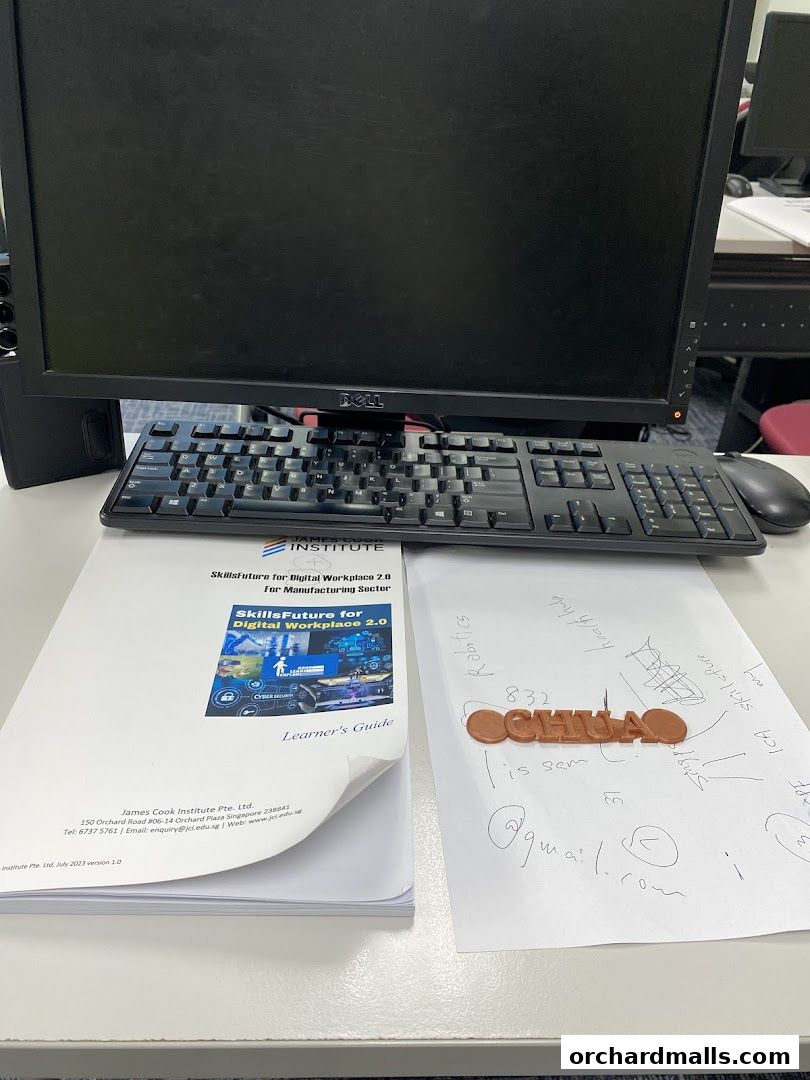 A desk with a computer, keyboard, mouse, and learning materials from James Cook Institute.